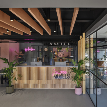 Modern reception area of J’adore Models featuring stylish design elements, neon signage, and greenery by Workshop Design Studio.