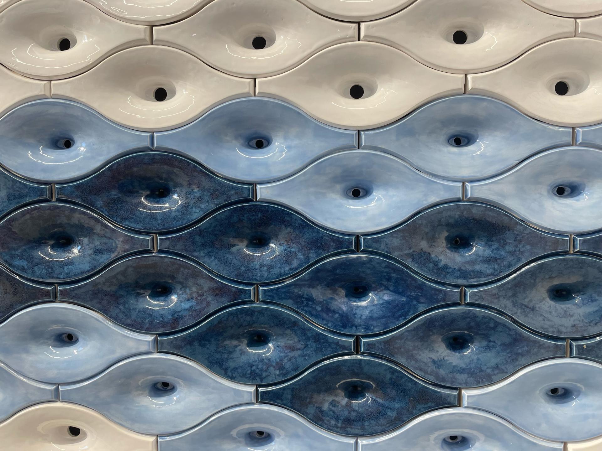 Ceramic tiles in wave patterns designed for sound absorption, showcasing varying shades of blue and white.