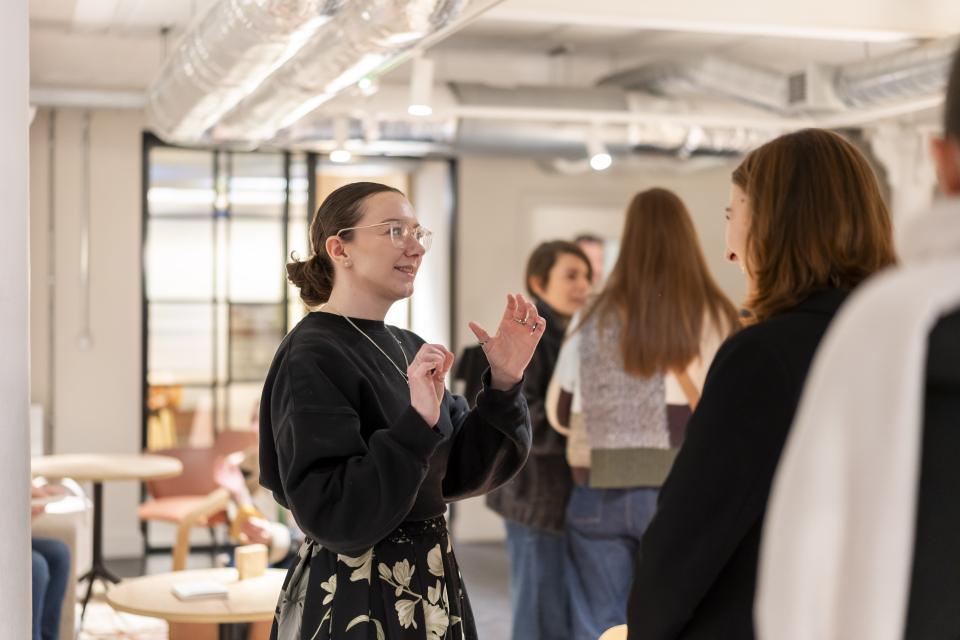 Celebrating creativity at Material Source Studio, a woman engages with guests during the vibrant community event.