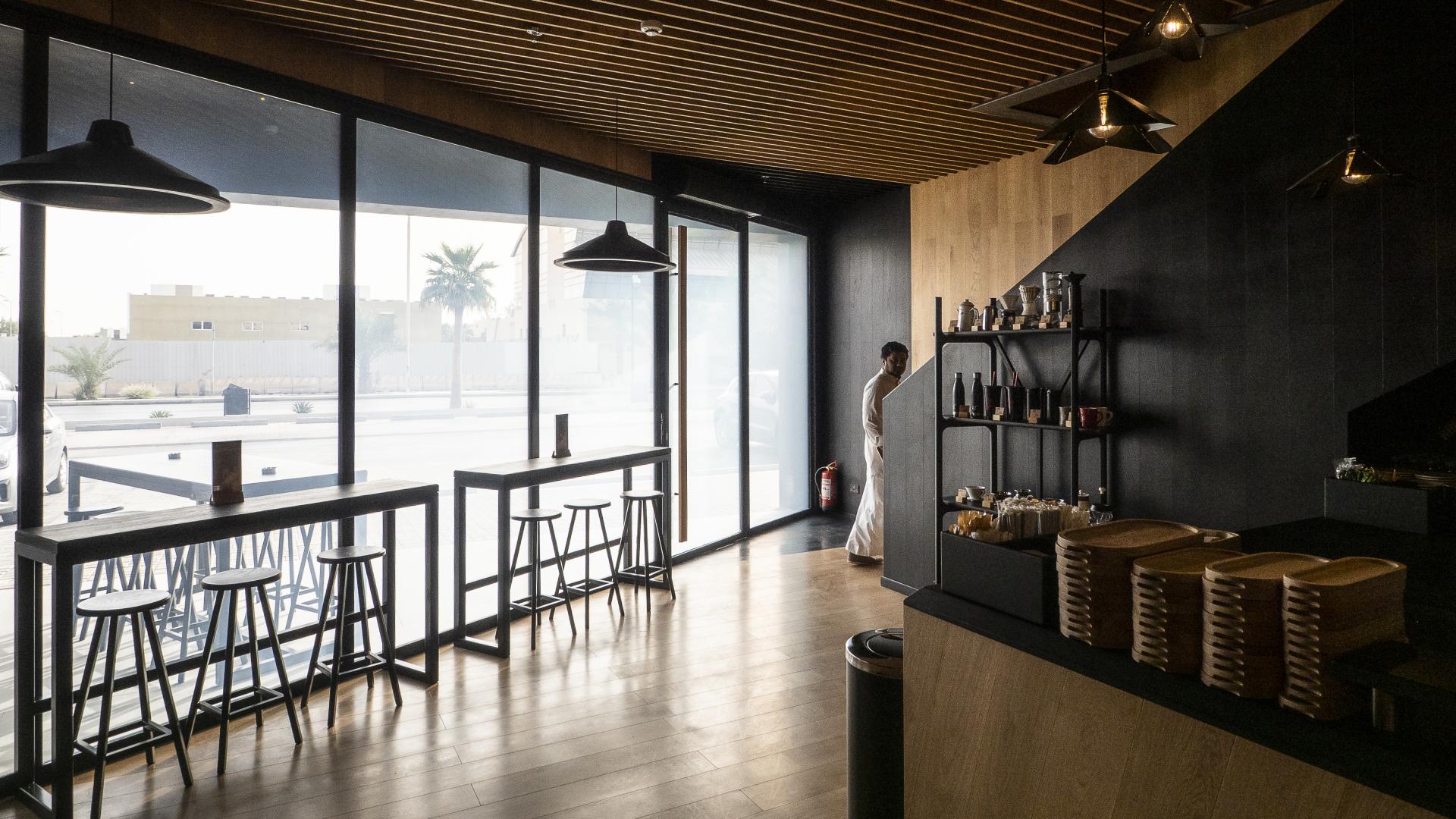 Modern coffee shop interior featuring sleek wood finishes, minimalist furniture, and large windows with natural light.
