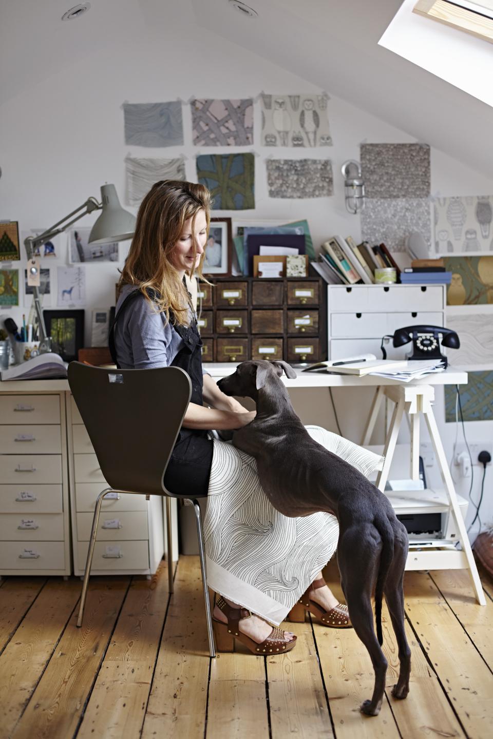Abigail Edwards interacts with her dog in her inspiring, nature-themed design studio filled with wallpaper samples.