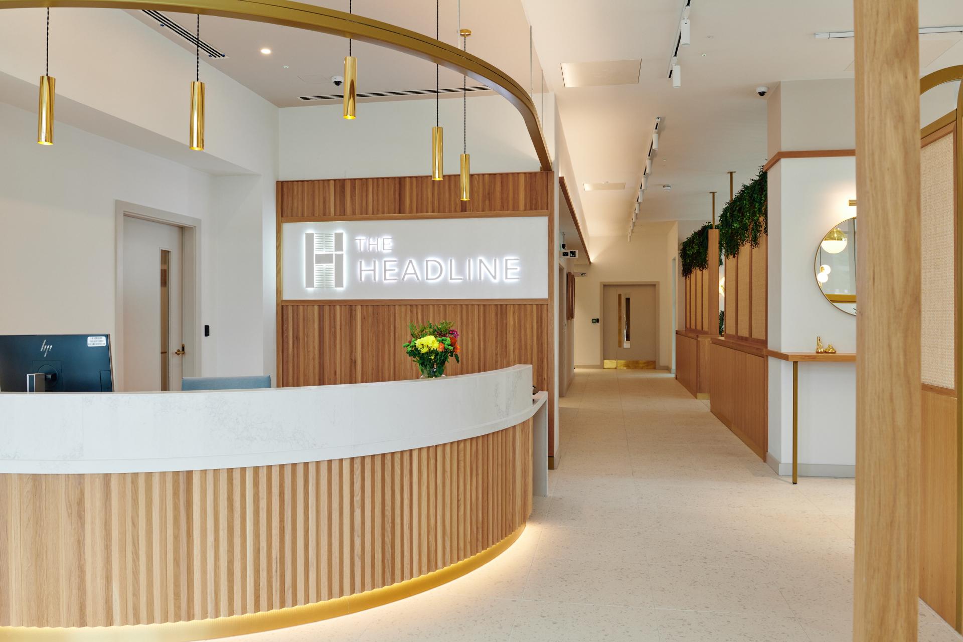 Modern reception area at The Headline in Leeds, featuring wooden accents and vibrant floral arrangement.