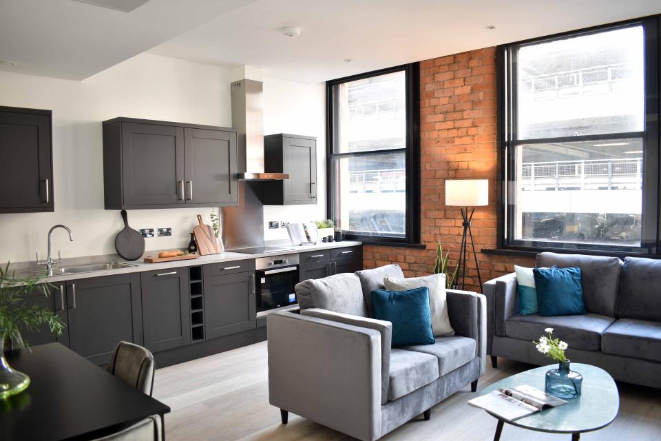 Luxury apartment interior showcasing modern kitchen and cozy living space in a transformed Victorian warehouse.