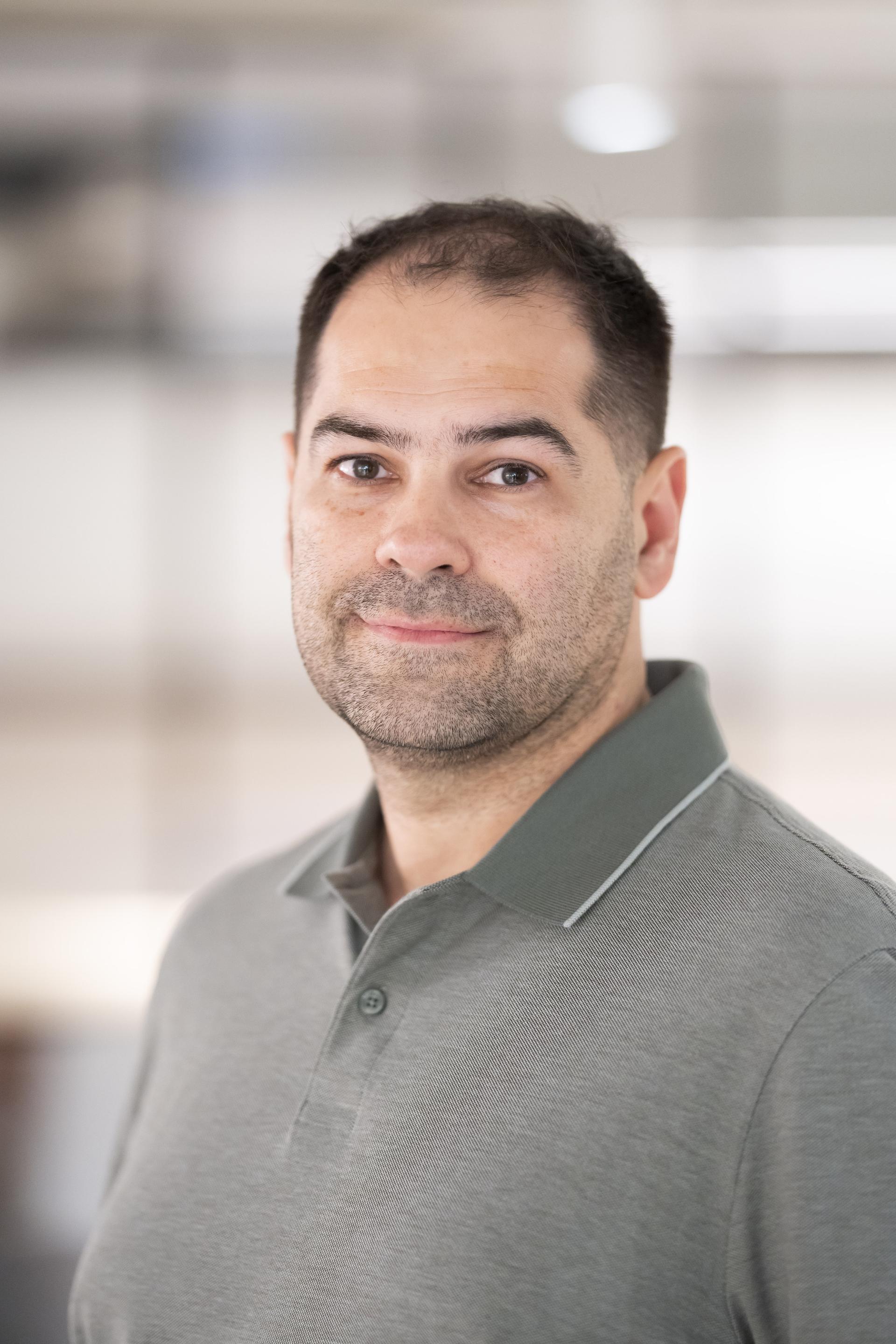Professional man in a gray polo shirt, reflecting on data's influence in modern workplace dynamics.