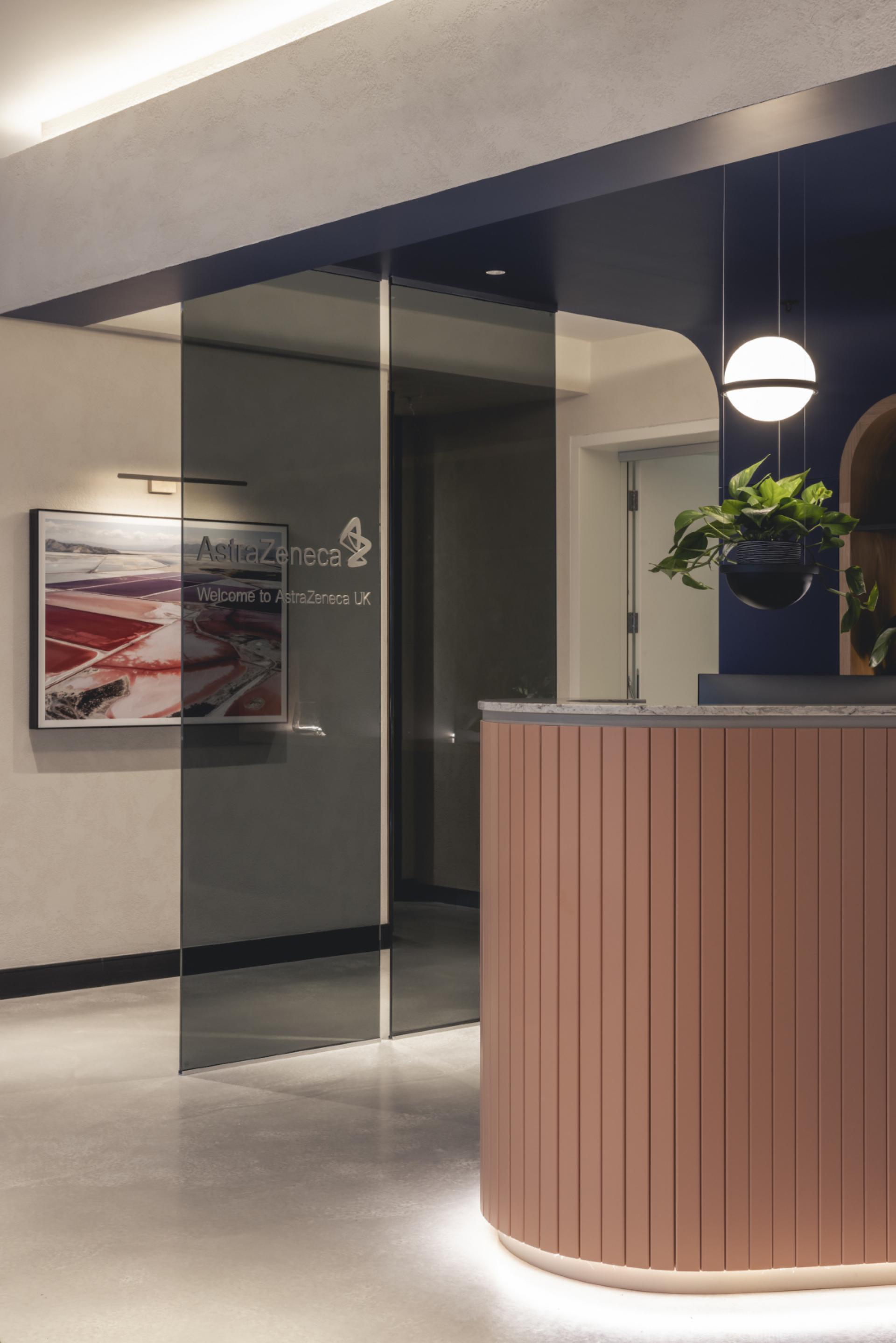 Modern reception area of AstraZeneca UK featuring glass doors, stylish decor, and vibrant plants.