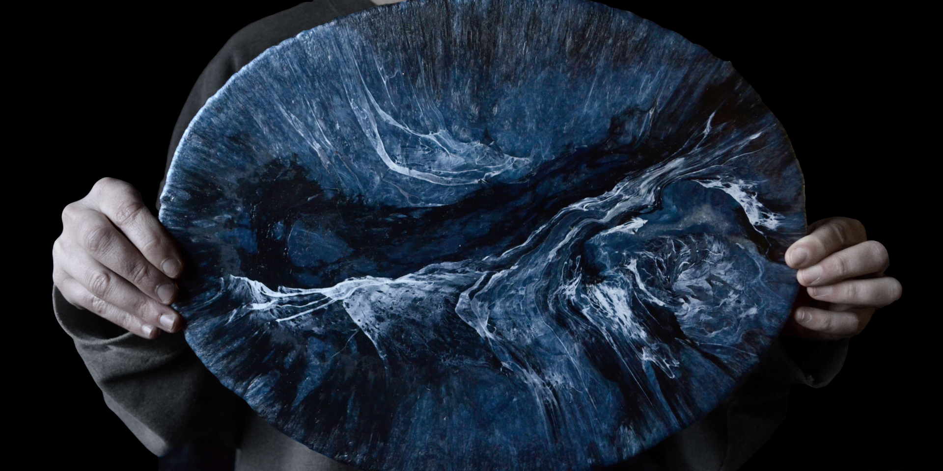A person holds a unique blue and white marbled plate made from recycled plastic, showcasing sustainable design innovation.