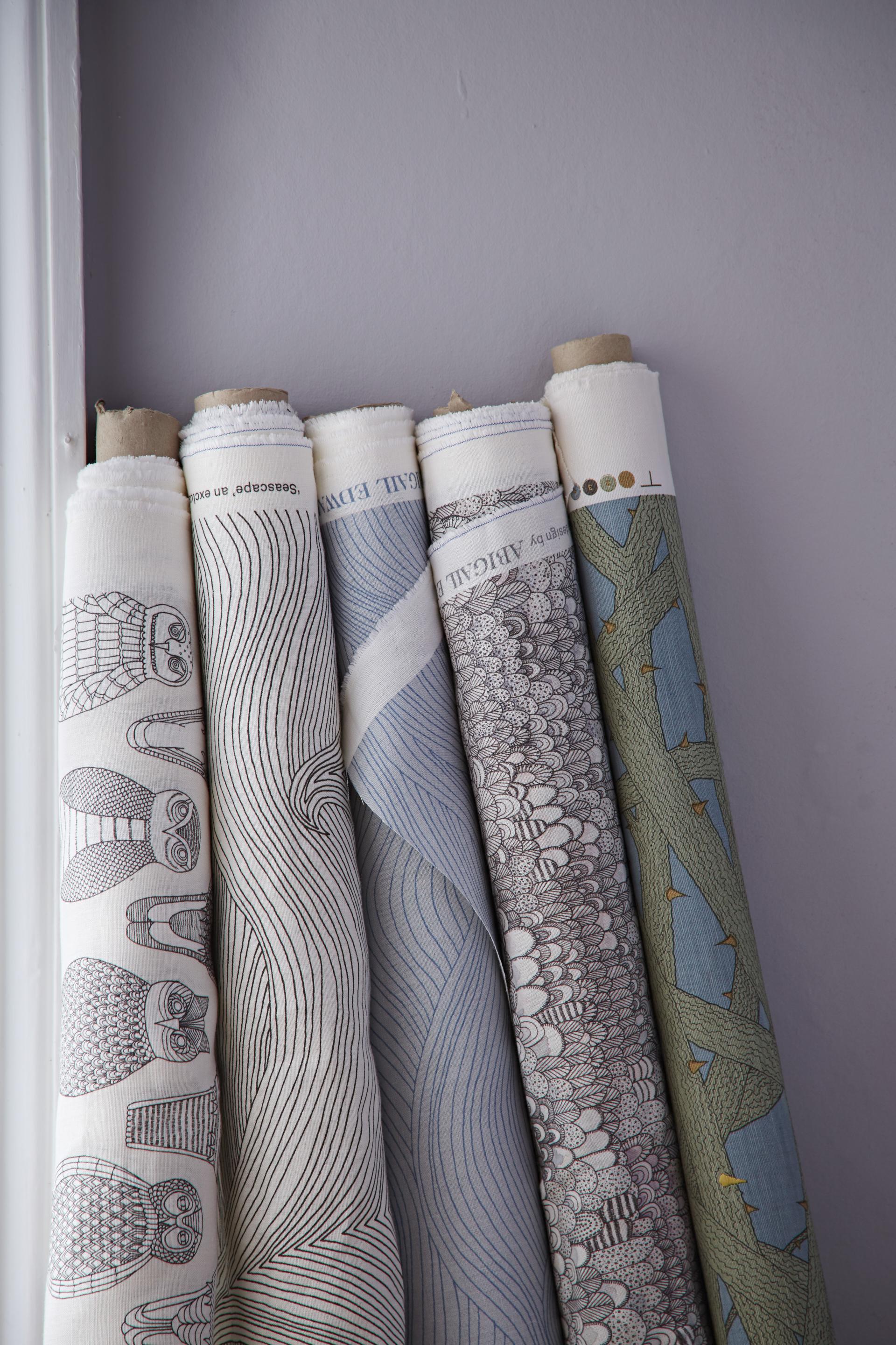 Rolls of decorative wallpaper showcasing intricate patterns inspired by nature, featuring designs by designer Abigail Edwards.