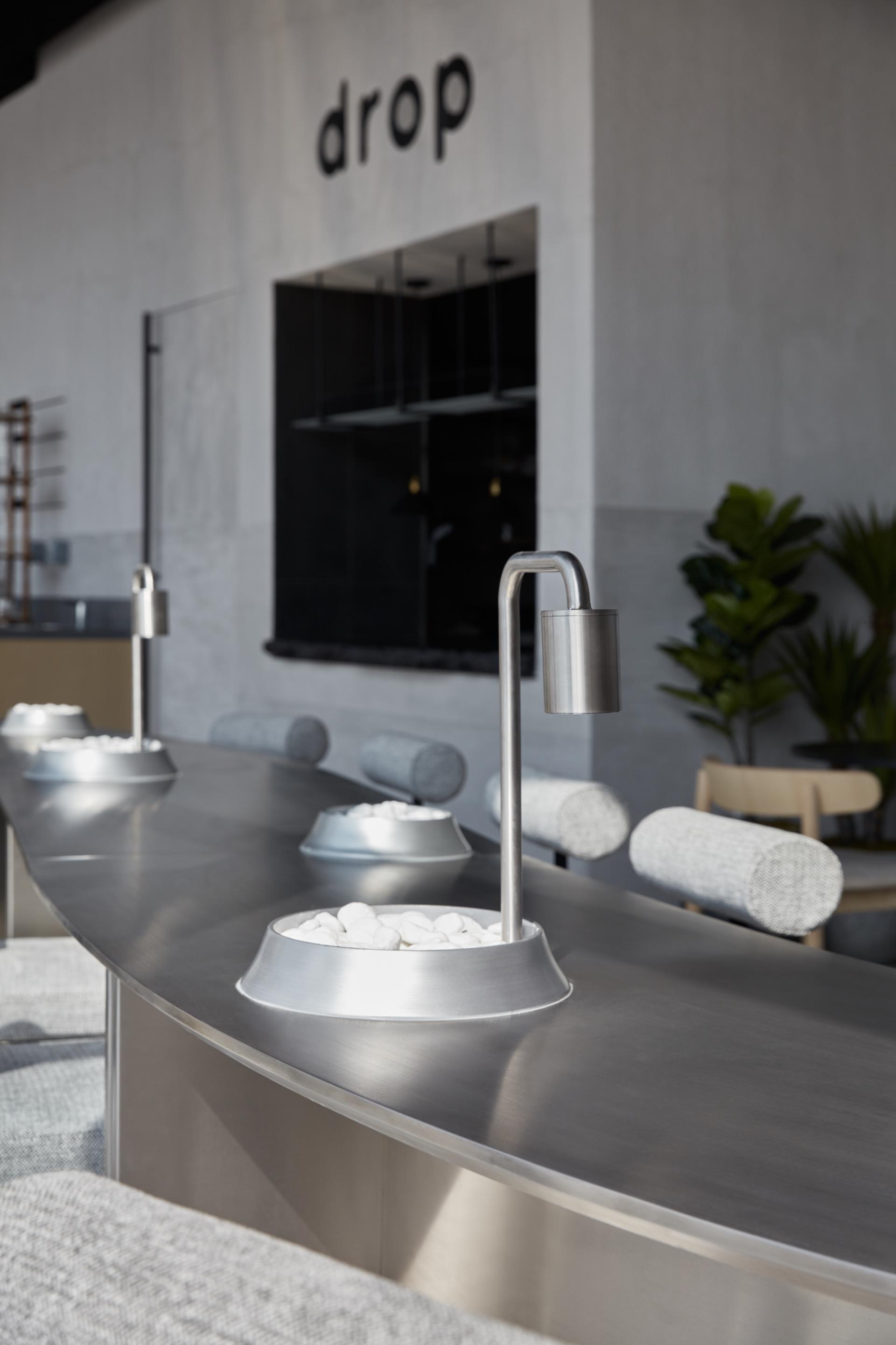 Monochrome coffee bar interior at Drop in Abu Dhabi, featuring sleek design elements and textured surfaces.