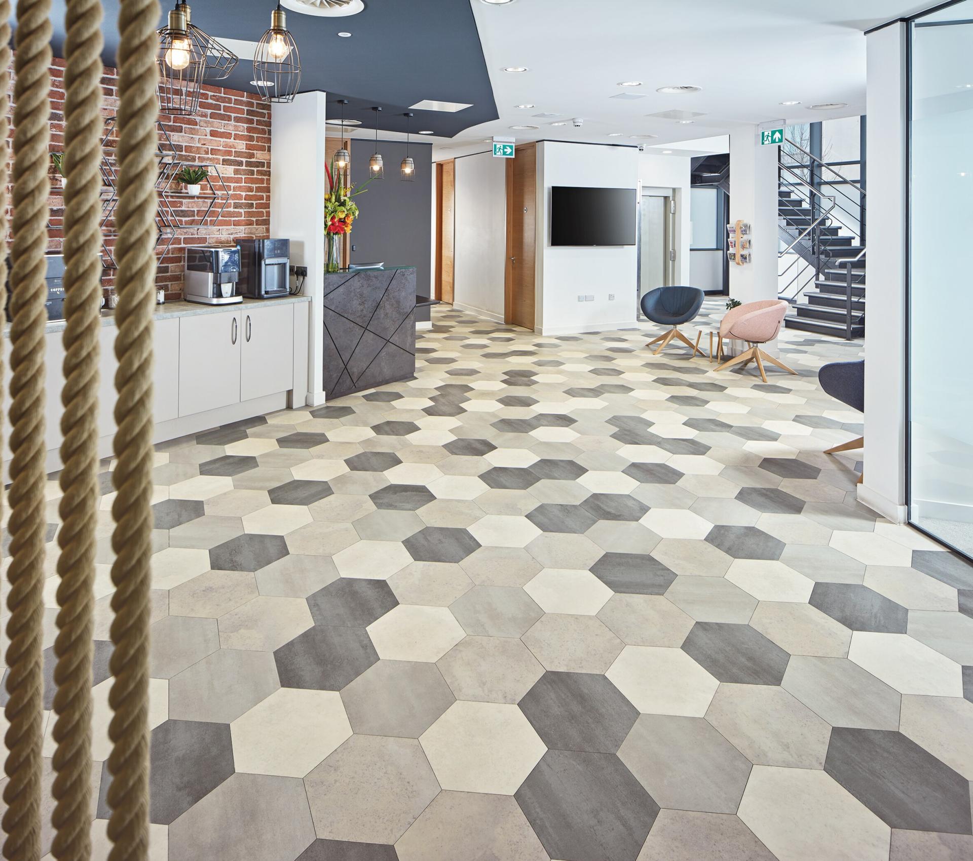Modern workplace interior featuring stylish hexagonal flooring and a welcoming hospitality area with coffee station and seating.