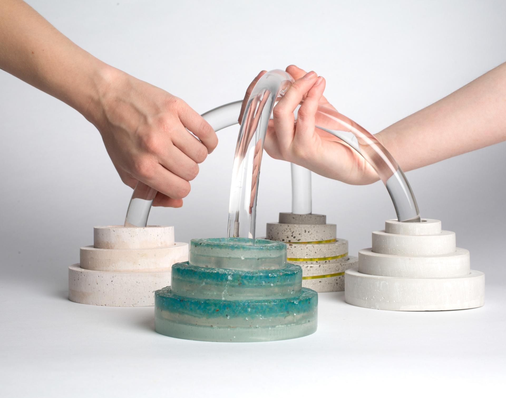Hands manipulating a unique water feature made of layered colored materials, showcased at the Surface Design Show 2019.