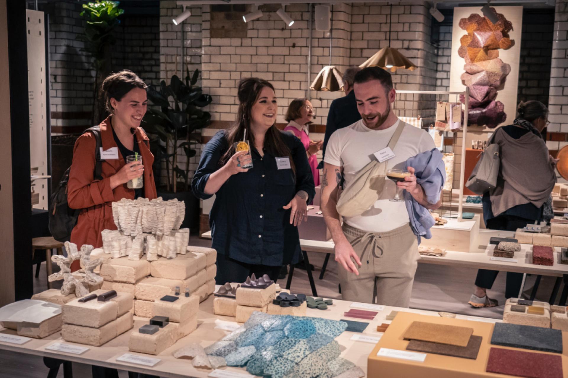 Visitors explore innovative sustainable materials at a design exhibition, showcasing eco-friendly projects and products.