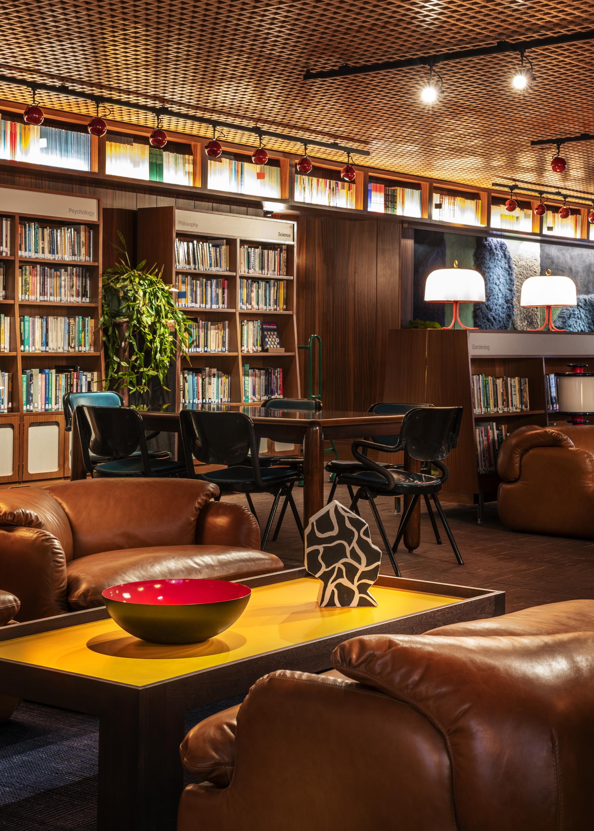 Cozy reading area in The Standard, London, featuring leather chairs, bookshelves, and modern decor elements.
