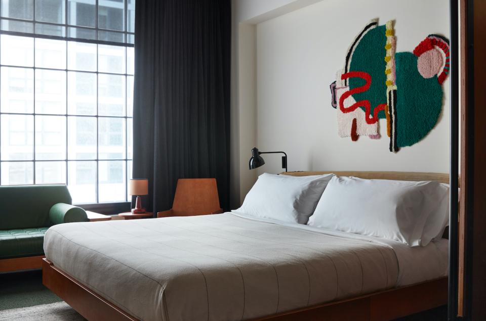 Stylish Ace Hotel Brooklyn guest room featuring contemporary decor, large windows, and an artistic wall hanging.
