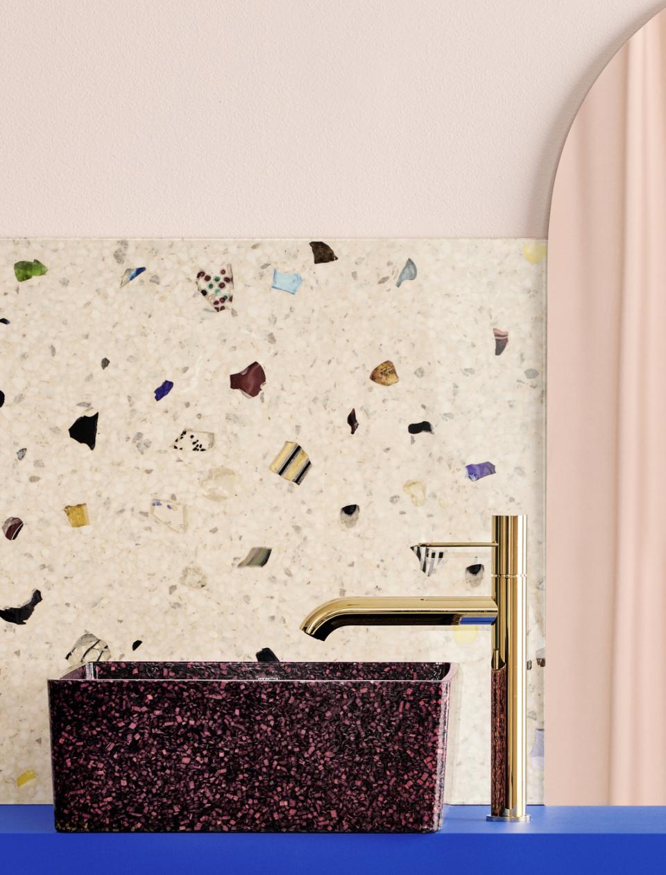 Stylish wood composite sink with gold faucet against a textured, colorful wall, highlighting sustainable washroom design.