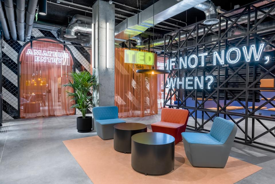 Stylish co-working space at The Student Hotel Barcelona featuring colorful seating, neon signs, and a vibrant atmosphere.