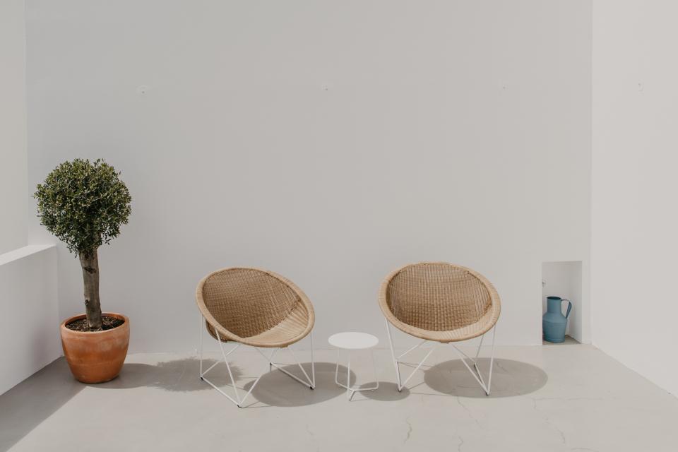 Stylish Acapulco chairs and a minimalist table create a serene outdoor space, harmonizing with nature and contemporary design.