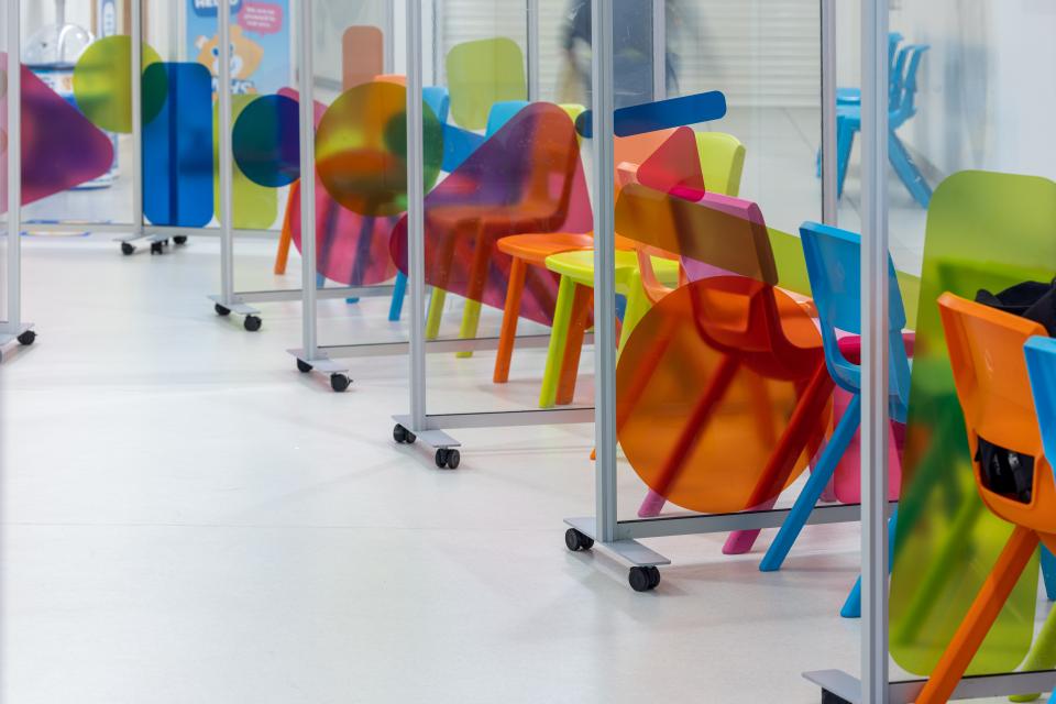 Colorful modern chairs and dividers in a children's hospital waiting area designed for comfort and calmness.