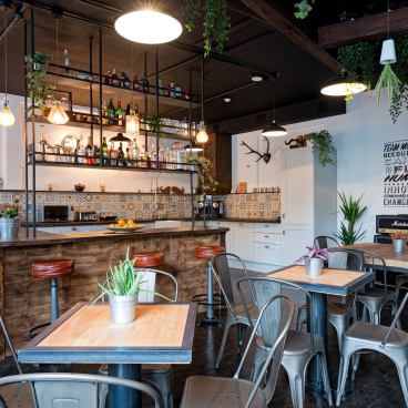 Industrial-inspired kitchen area of Movember Foundation’s London headquarters featuring plants, wood accents, and vibrant decor.