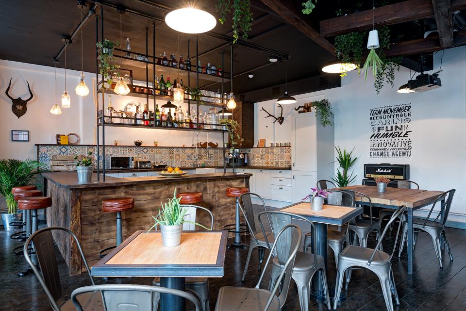 Industrial-inspired kitchen area of Movember Foundation’s London headquarters featuring plants, wood accents, and vibrant decor.