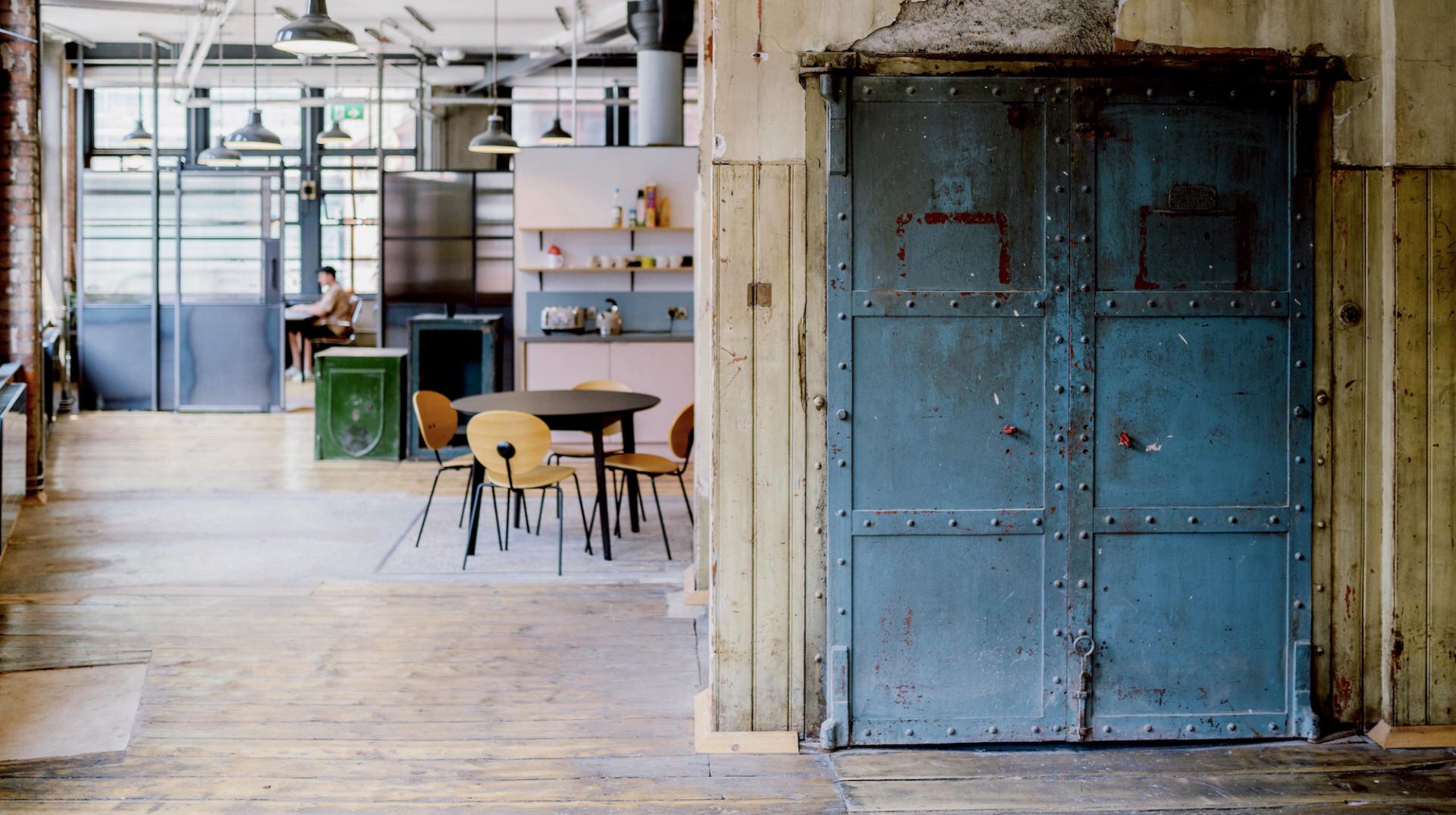 Creative studio interior showcasing vintage design, featuring a blue metal door and a modern workspace.