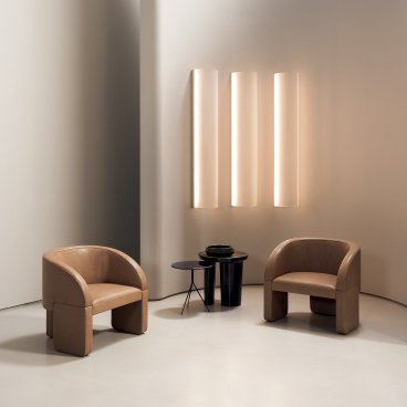 Stylish contemporary armchairs and minimalist lighting in a modern interior setting at Baxter's showcase in London.