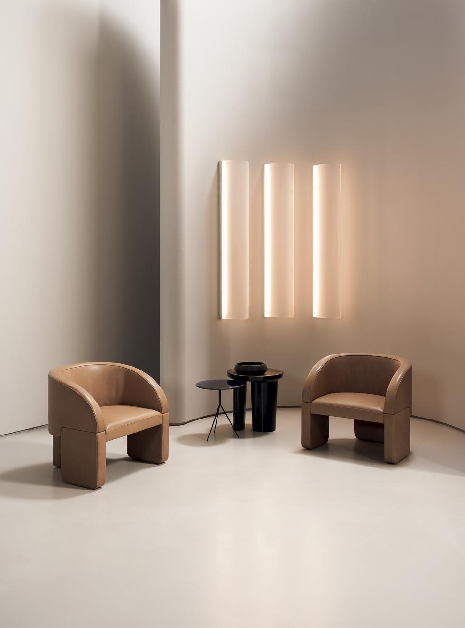 Stylish contemporary armchairs and minimalist lighting in a modern interior setting at Baxter's showcase in London.