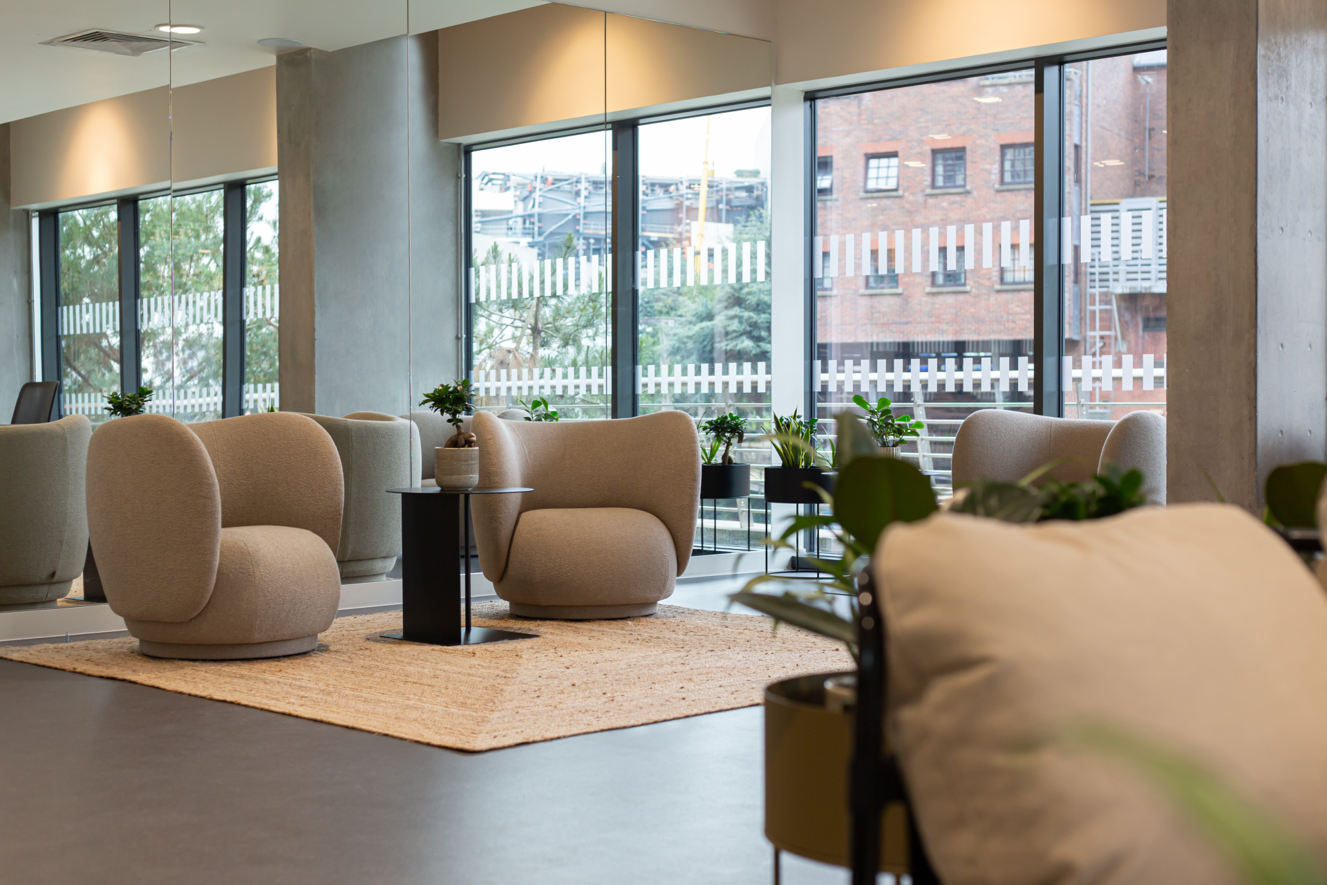 Stylish lounge area featuring modern furniture, plants, and large windows, embodying urban design and collaboration principles.