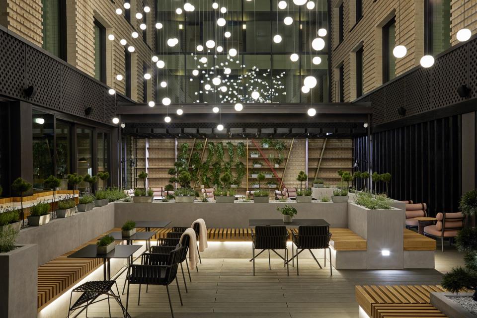 Stylish interior design of PURO Kraków Kazimierz features lush greenery and contemporary seating with ambient lighting.