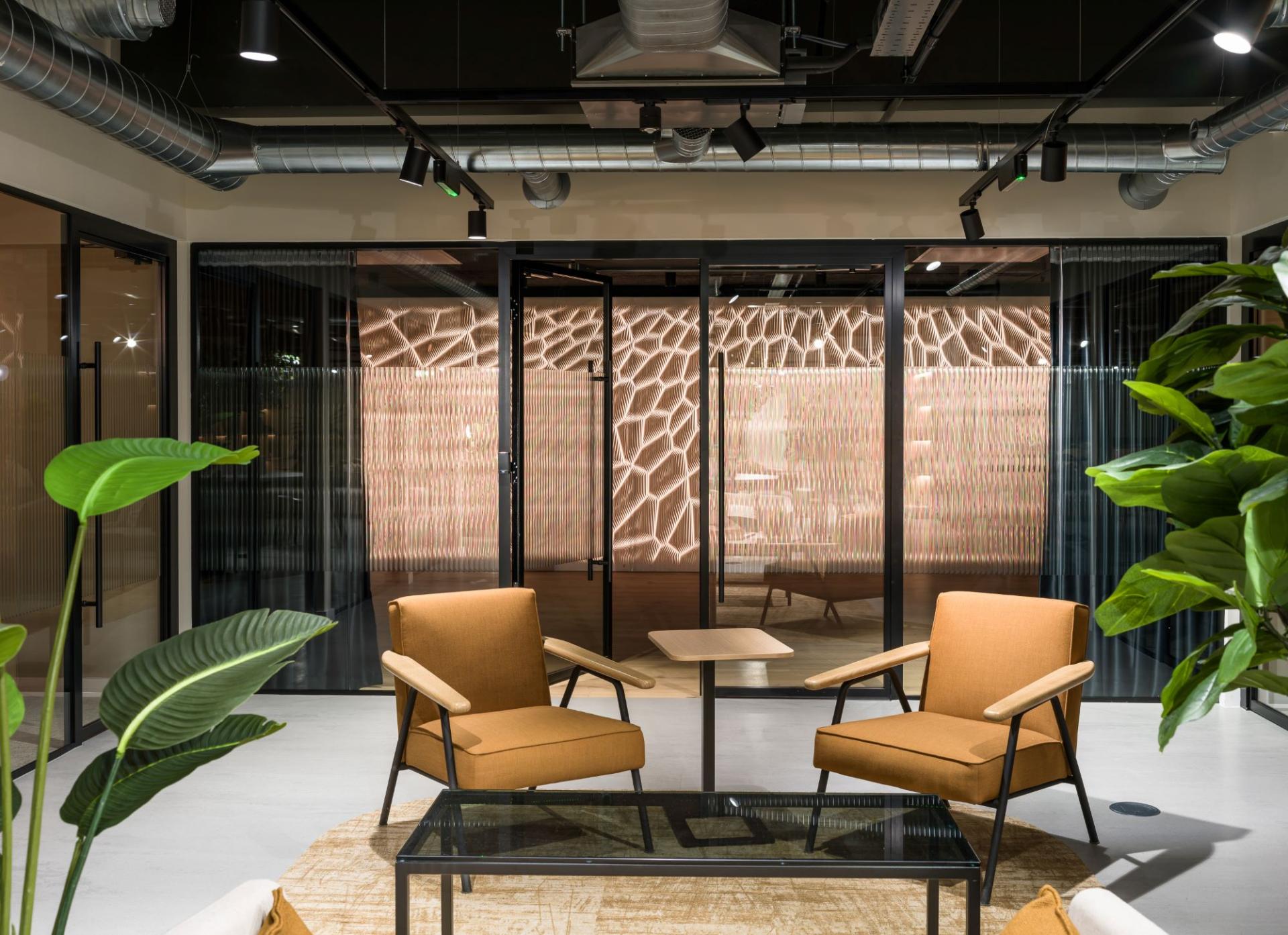 Modern lounge area featuring stylish chairs and a patterned glass partition at the Glasshouse, Alderley Park.