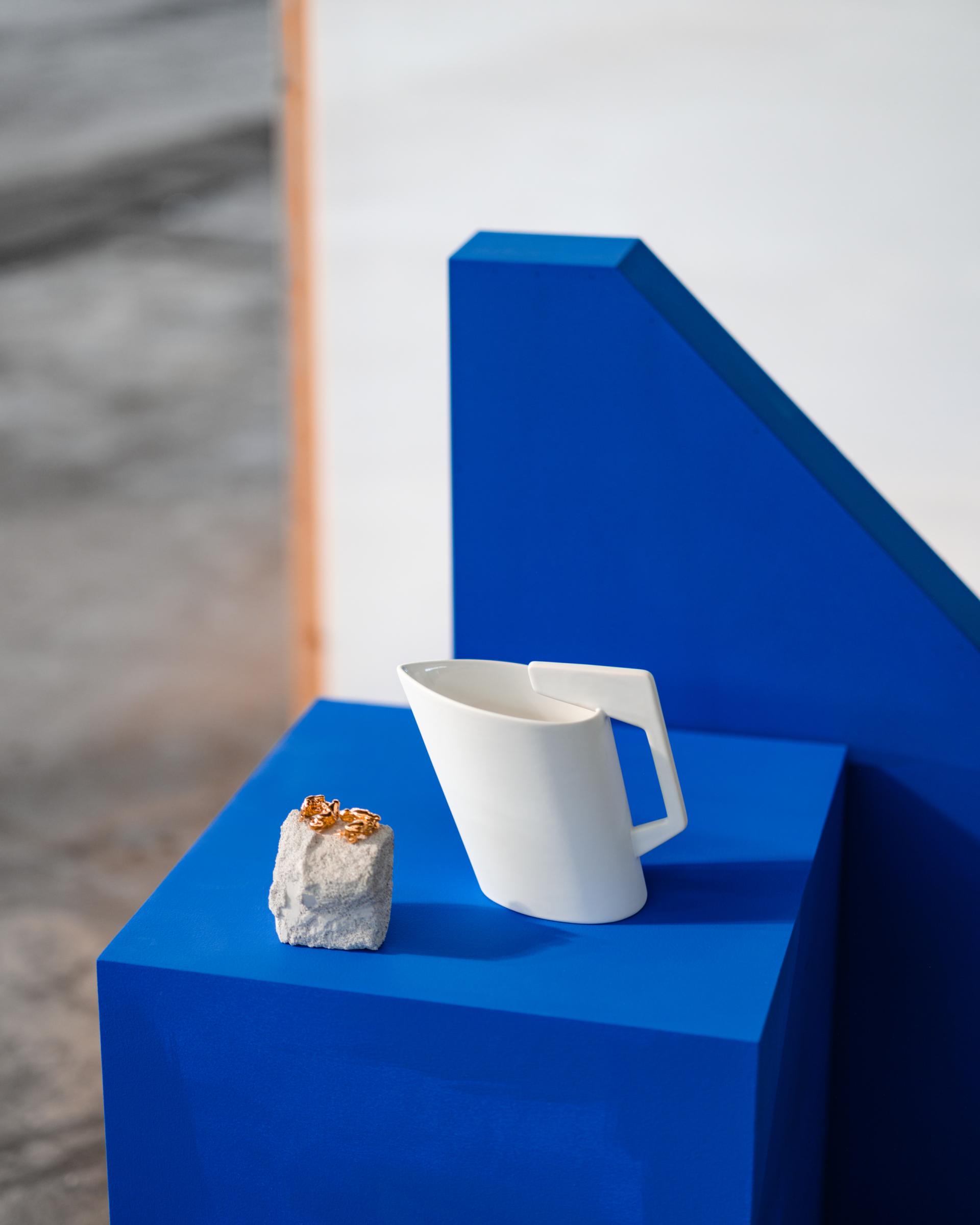 Ceramic pitcher and golden rings displayed on a vibrant blue pedestal at Dundee Design Festival 2024.