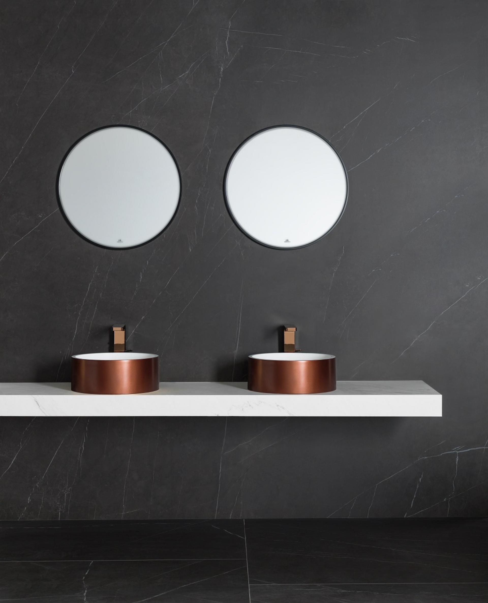 Elegant bathroom design featuring earthy clay-toned vessel sinks and circular mirrors against a dark stone backdrop.