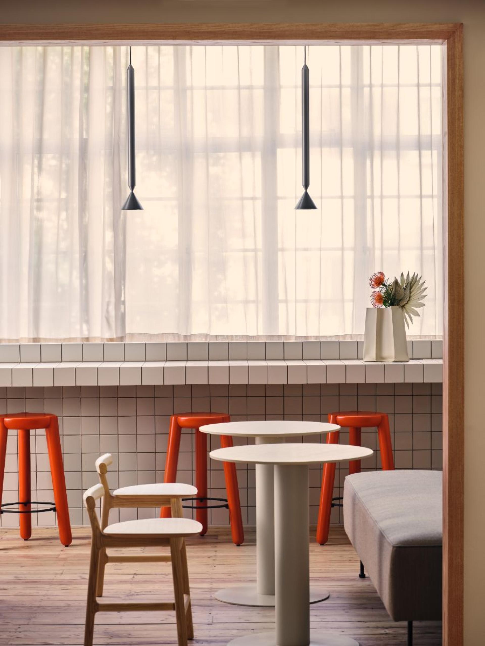 Brightly lit flexible workspace featuring modern furniture, orange stools, and natural decor, ideal for collaborative office environments in London.