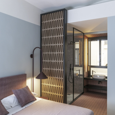 Stylish bedroom with modern decor, showcasing a partitioned bathroom area in a Trastevere apartment design.