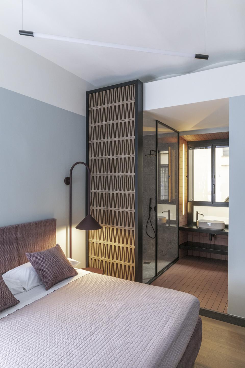 Stylish bedroom with modern decor, showcasing a partitioned bathroom area in a Trastevere apartment design.