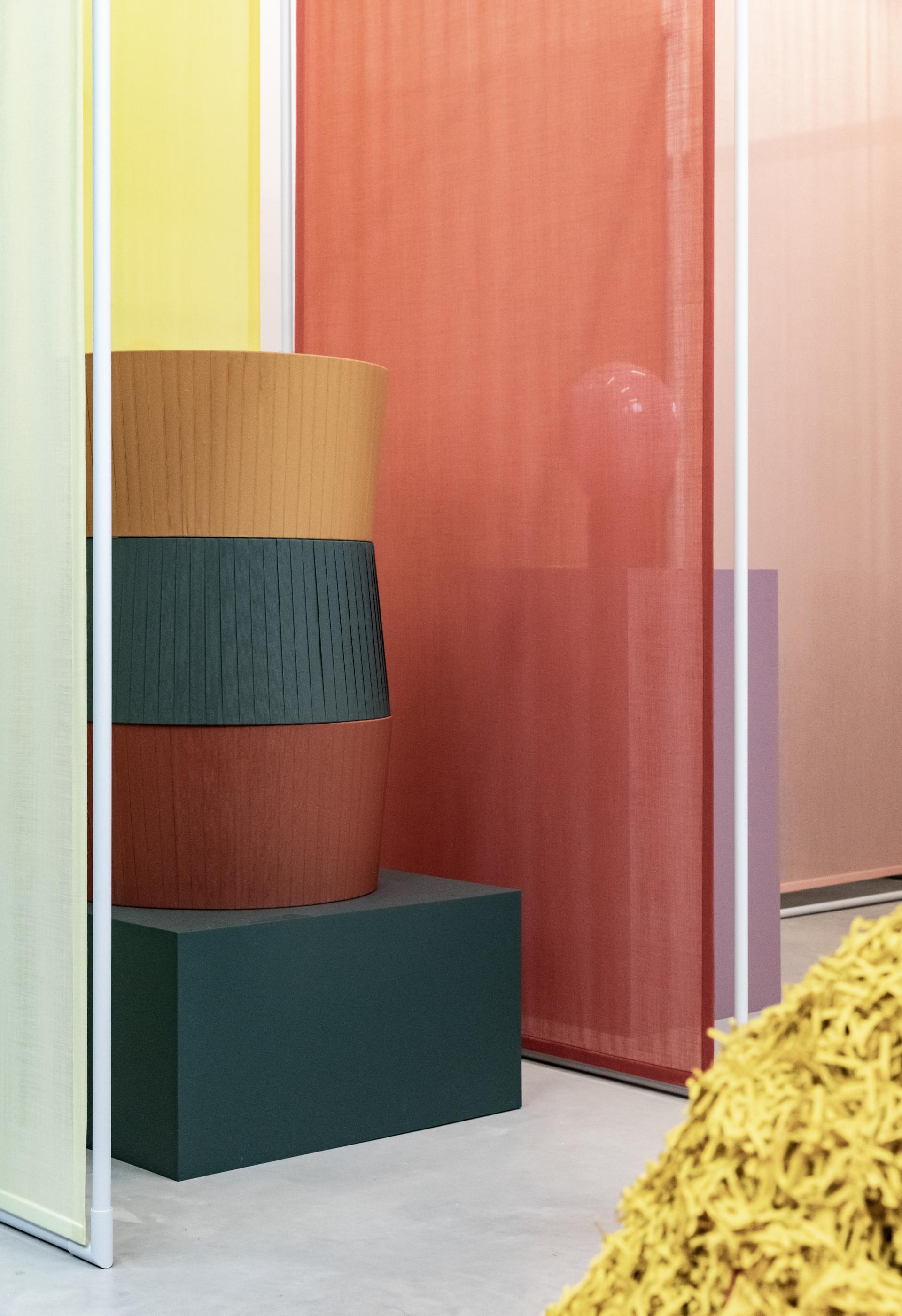 Colorful stacked planters and fabrics showcase bio-based materials in a modern design environment, reflecting Raw Color's innovative approach.