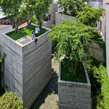 Contemporary architectural design featuring unique green-roofed structures surrounded by lush greenery and a cobblestone pathway.