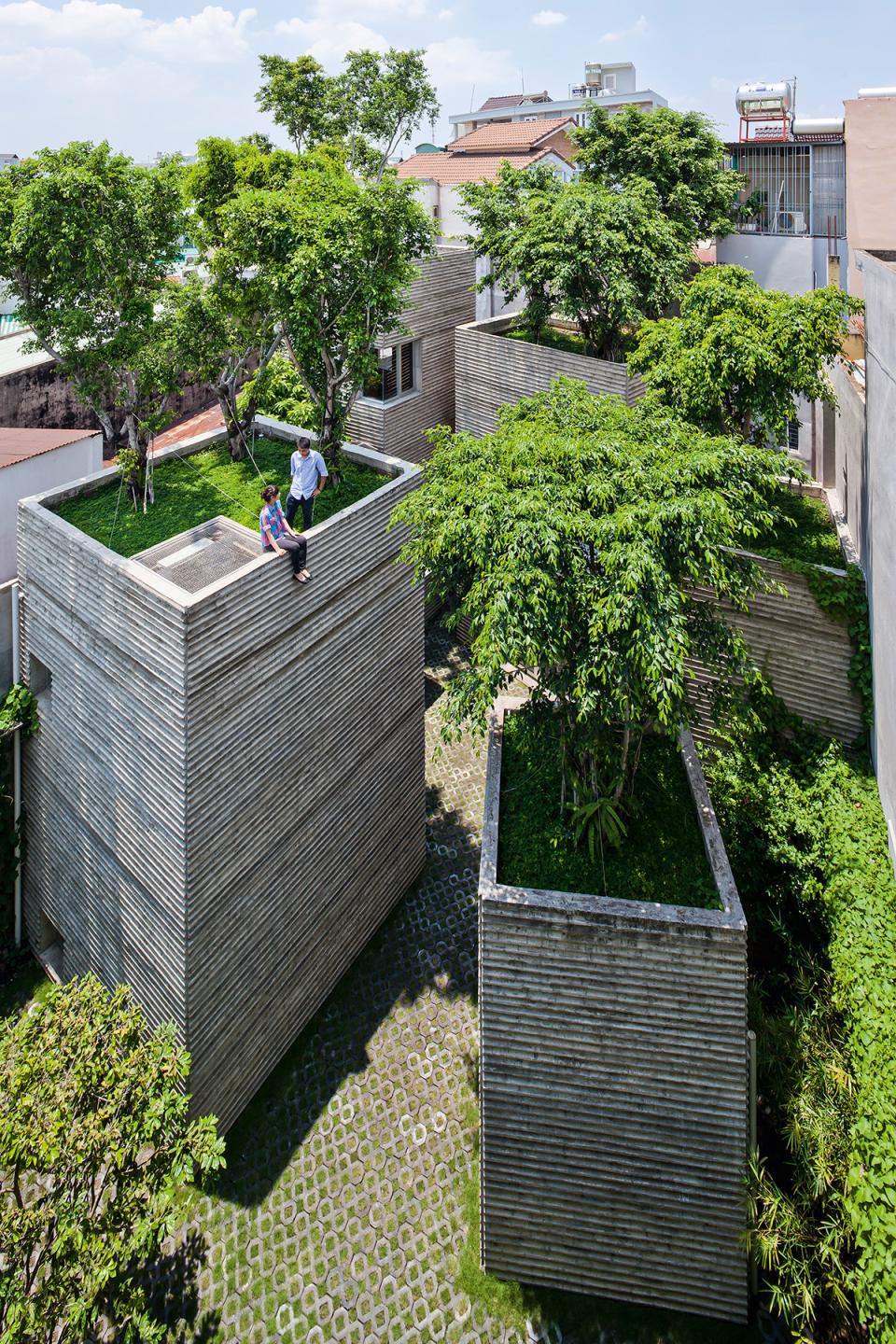 Contemporary architectural design featuring unique green-roofed structures surrounded by lush greenery and a cobblestone pathway.