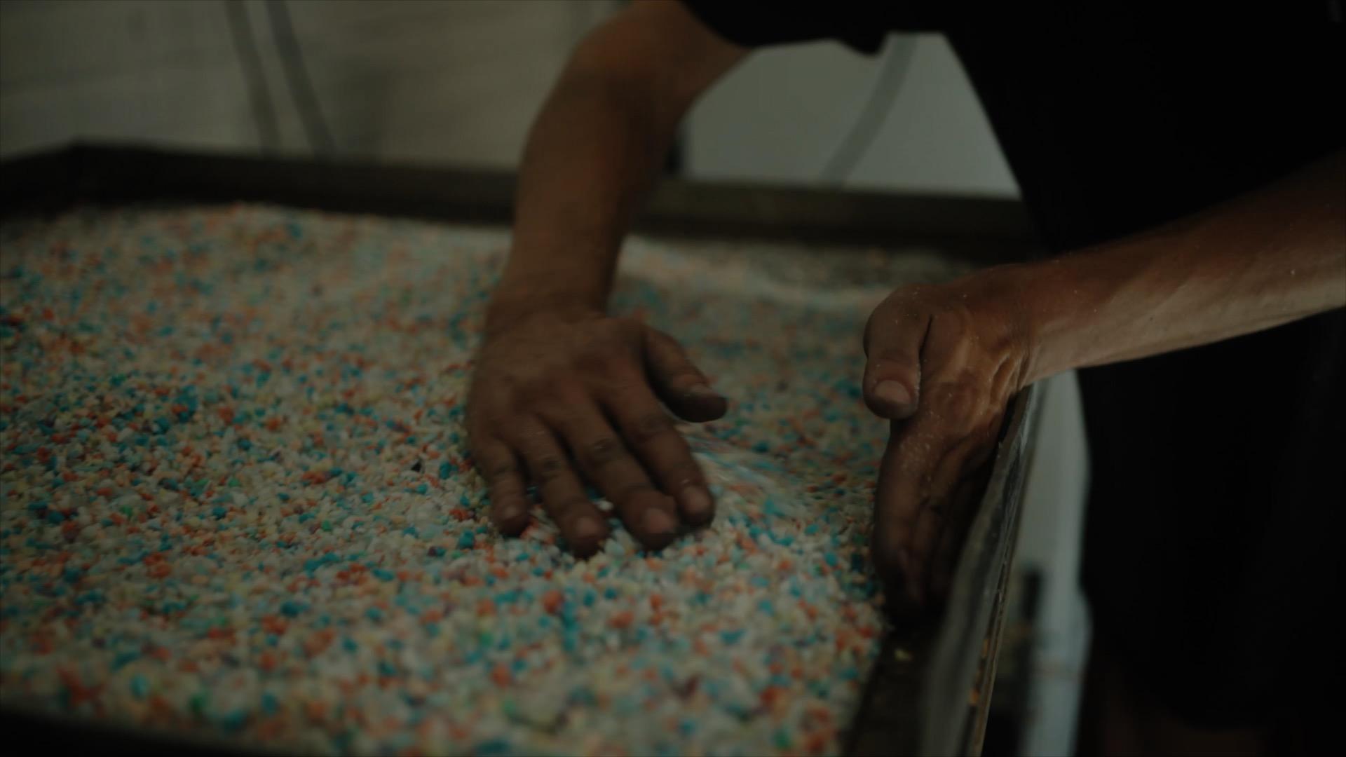 Hands sorting colorful material in a tray, representing Surface Matter's innovative circular Material Rescue initiative for sustainable design.