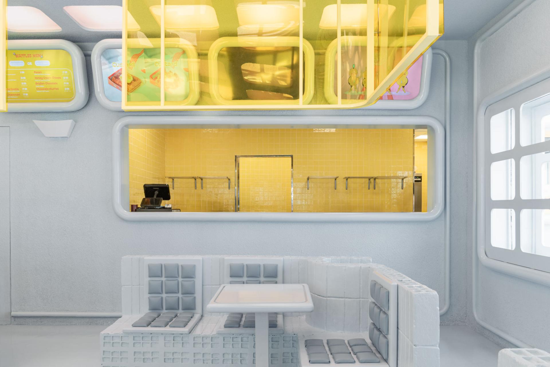 Brightly colored interior of Novu Waffle features modern seating and a futuristic serving area, designed by Masquespacio.