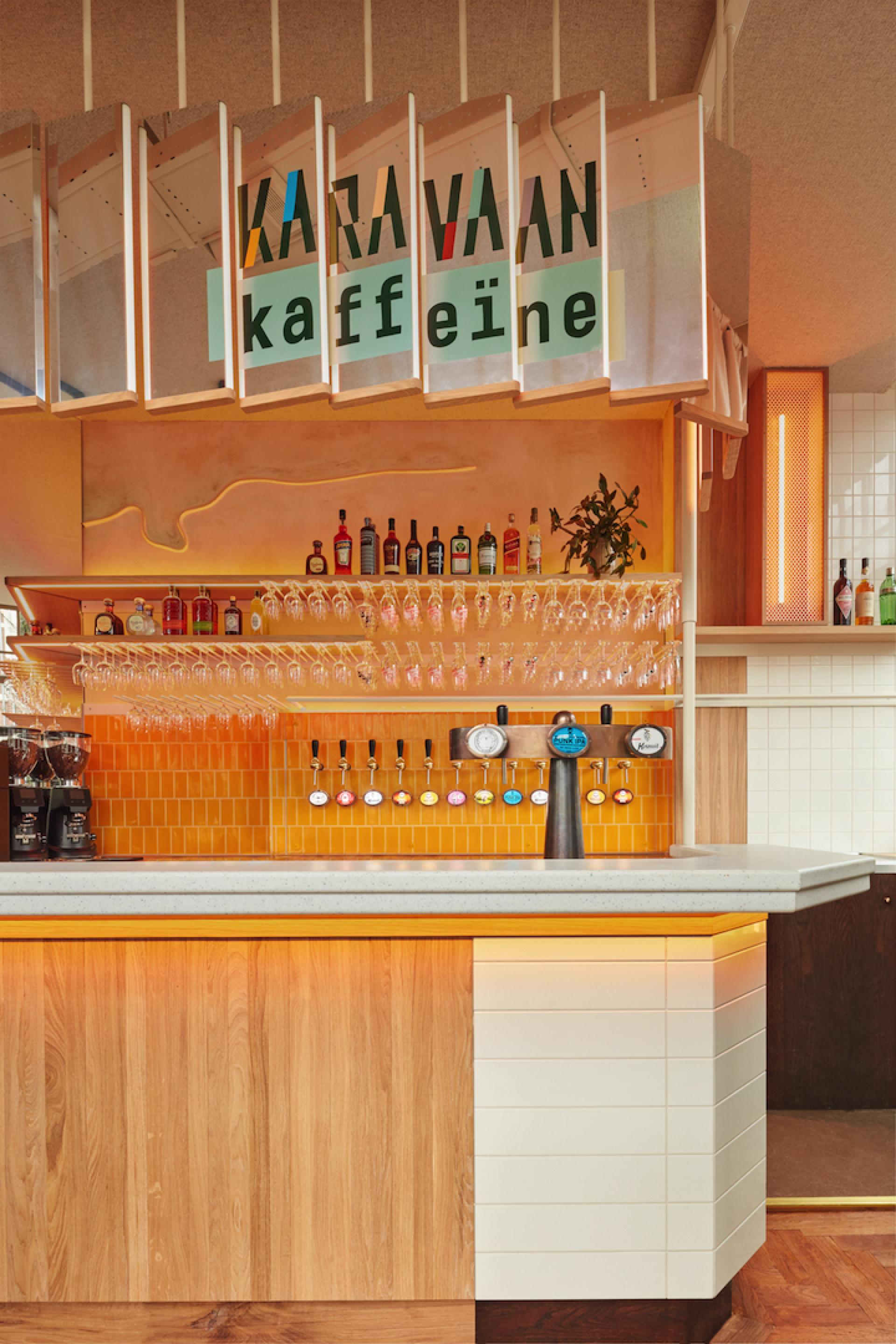 Stylish bar interior of Karavaan featuring colorful liquor selection, glassware, and modern design elements in Amsterdam.