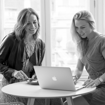 Co-CEOs Victoria Firth and Rhonda Curliss of Grey Lemon discussing business strategies over laptop at a table.