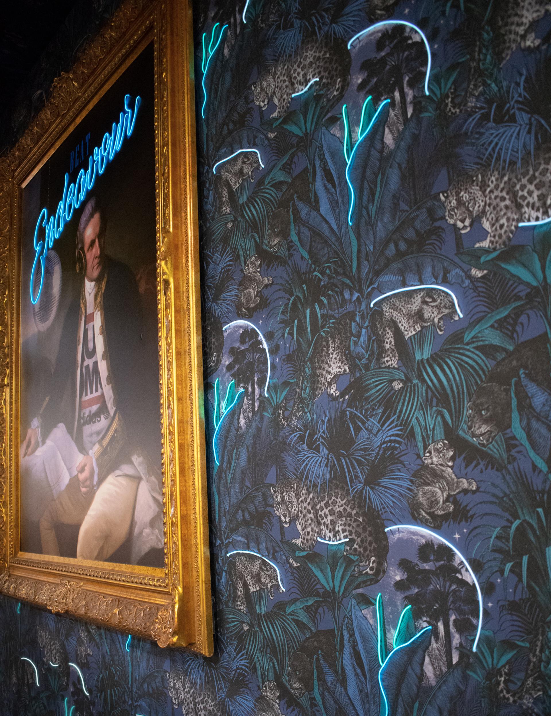 Luxurious interior showcasing vibrant wallpaper with leopards and foliage, framed artwork, and modern neon accents.