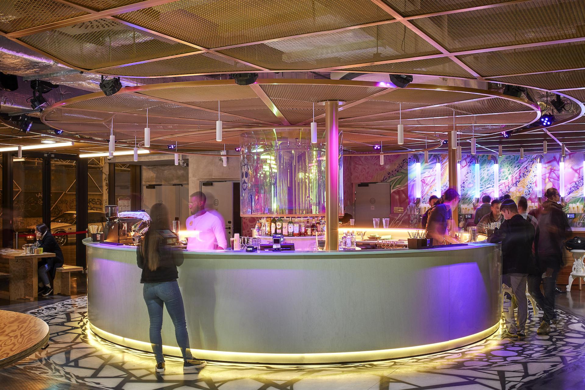 Stylish bar area at JO&JOE Paris Gentilly, featuring vibrant lighting and a lively atmosphere, award-winning hospitality.