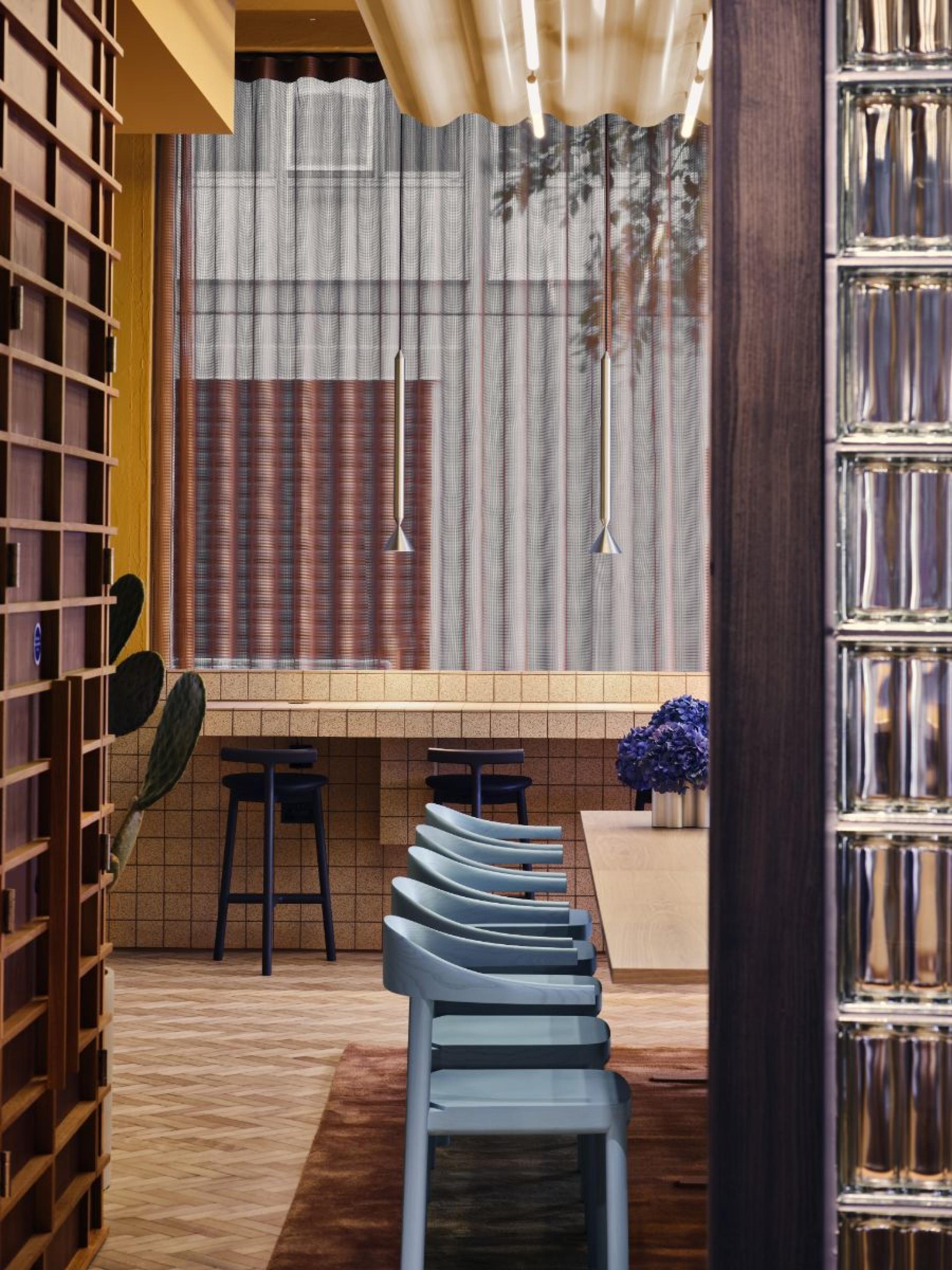 Modern flexible workspace interior featuring blue chairs, wood decor, and vibrant lighting in a London office setting.