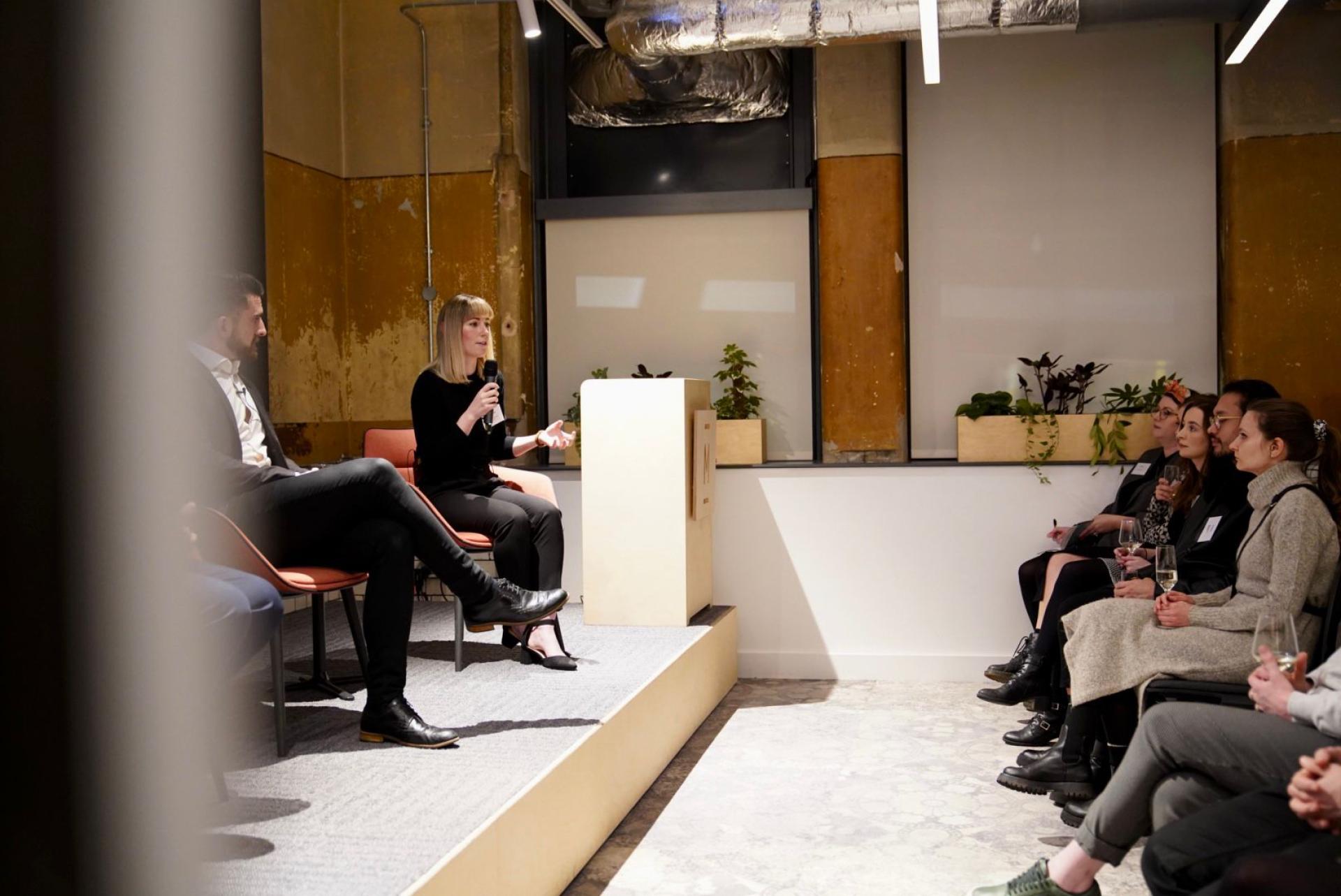 A speaker discusses sustainability concepts at a seminar with an engaged audience in a modern setting.
