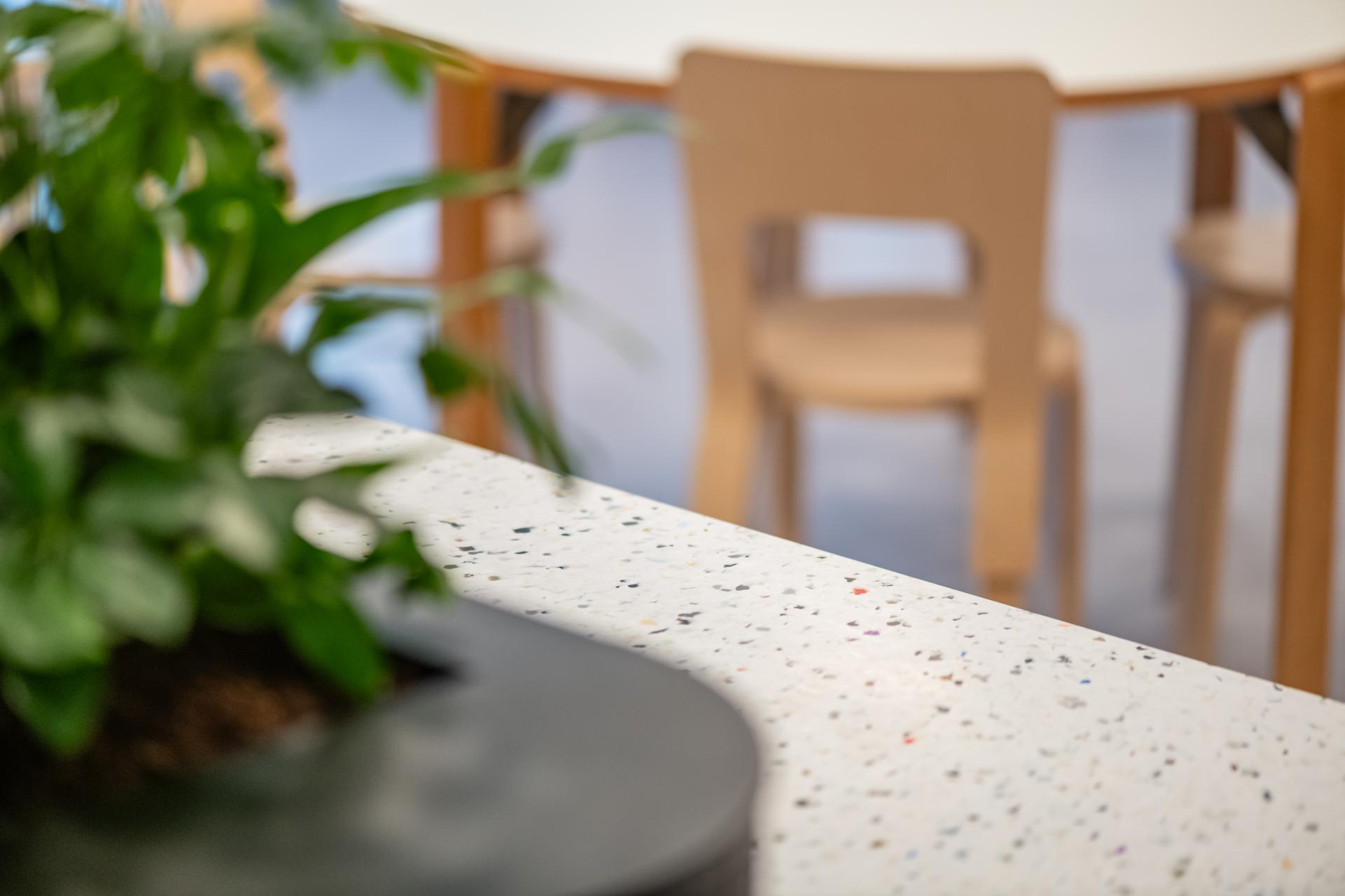 Modern office workspace with terrazzo countertop and greenery, reflecting innovative design principles by iDEA for Conferma.