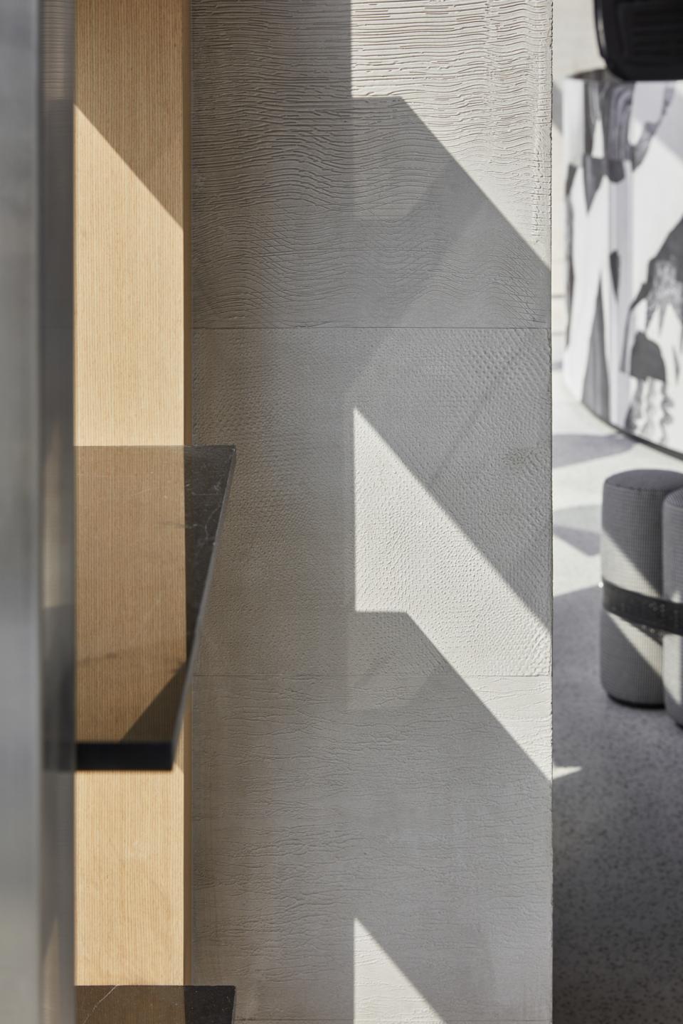 Minimalist interior design of Drop Coffee in Abu Dhabi, featuring textured walls and natural light creating dynamic shadows.