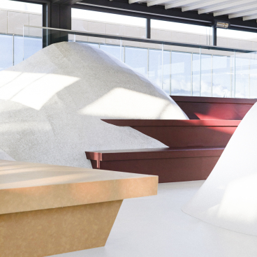 Modern exhibition space featuring flowing shapes, soft curves, and a winter landscape concept with textured surfaces and natural light.