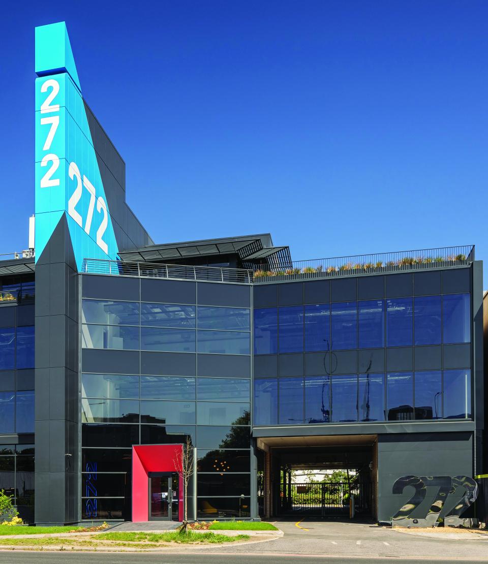 Modern office building facade featuring large glass windows, vibrant blue and red accents, and distinctive signage for 272GA.