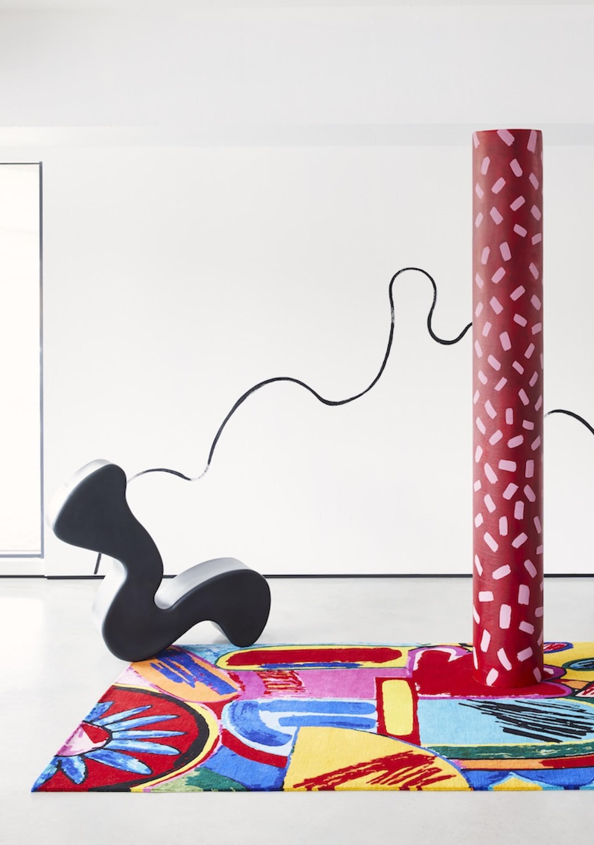 Bold black sculpture and vibrant patterned rug create a contemporary artistic scene, highlighting John Booth's unique design style.